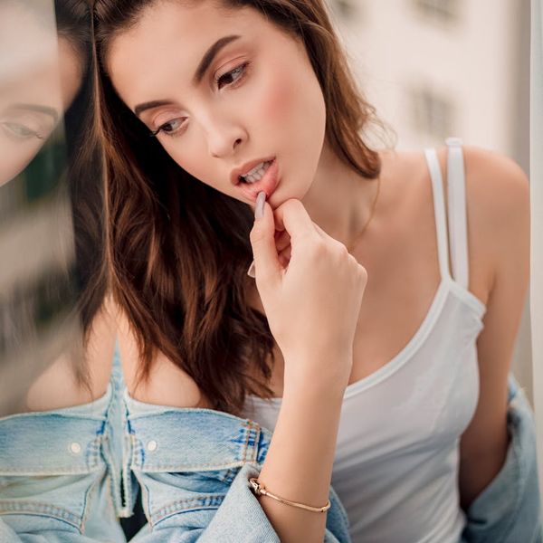 Person looking out a window with a relaxed and clear expression, bathed in soft light.